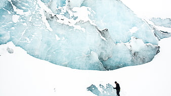 Aerial view of mountaineer climbing blue glacier ice wall