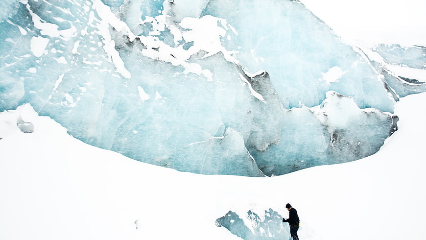 Aerial view of mountaineer climbing blue glacier ice wall