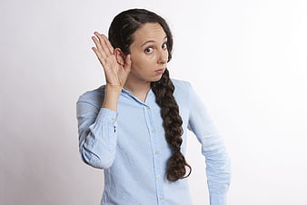 Young woman with braided hair cupping ear to listen intently