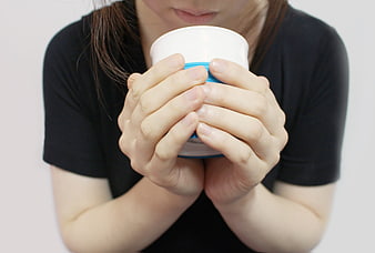Woman holding white cup with blue stripe against white background