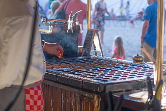 Street vendor cooking Dutch mini pancakes on a griddle