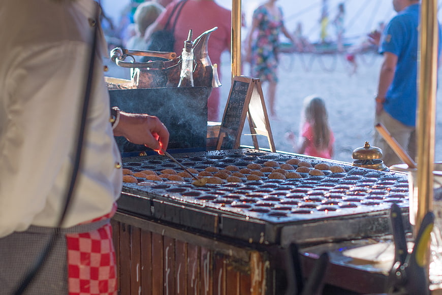 Street vendor cooking Dutch mini pancakes on a griddle