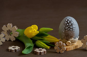 Easter still life with yellow tulips, decorated egg, and wooden flowers