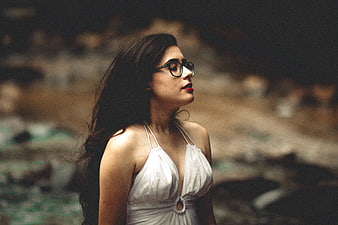 Woman with Glasses in White Dress Looking Up Outdoors