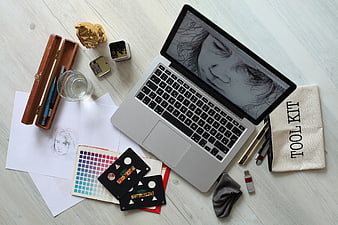 Creative workspace with laptop, sketch, and art supplies on wooden desk