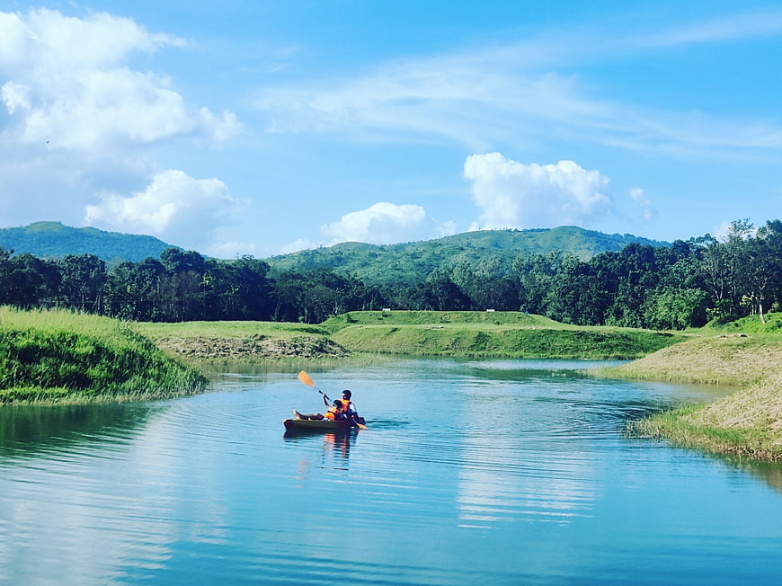 Couple kayaking on calm river surrounded by green hills
