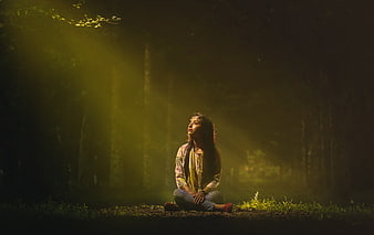 Young Woman Sitting in Misty Forest with Sunbeams
