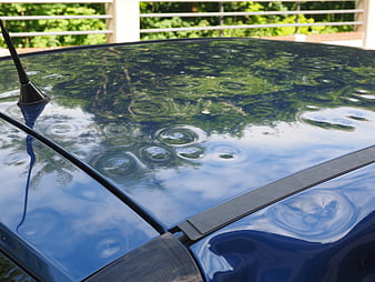 Hail damage on blue car roof with dents and ripples