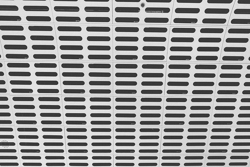 Black and white geometric pattern of pill-shaped slots on metal panels