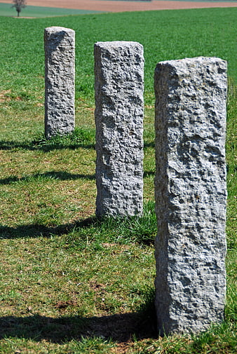 Three weathered stone pillars standing in a grassy field