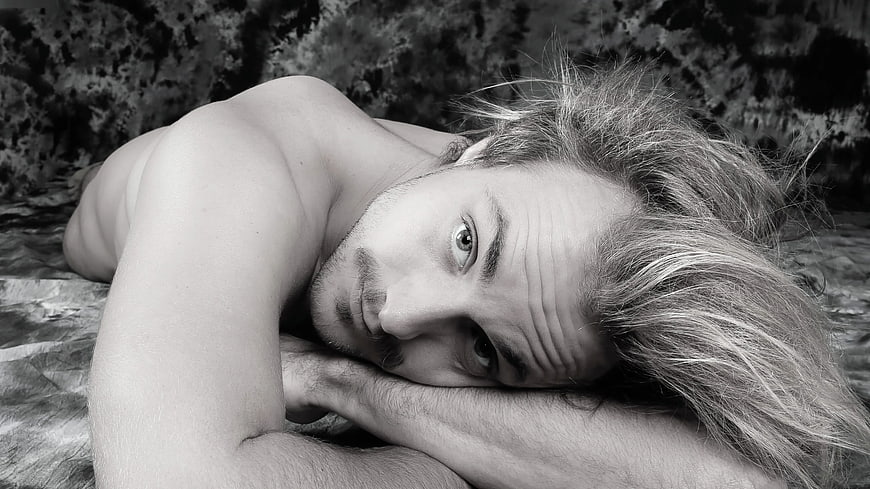 Black and white portrait of shirtless man lying down