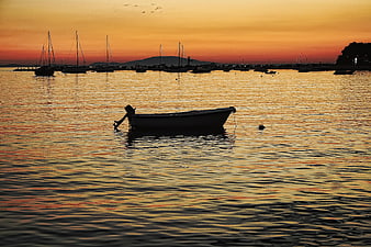 Silhouette of small boat in harbor at golden sunset