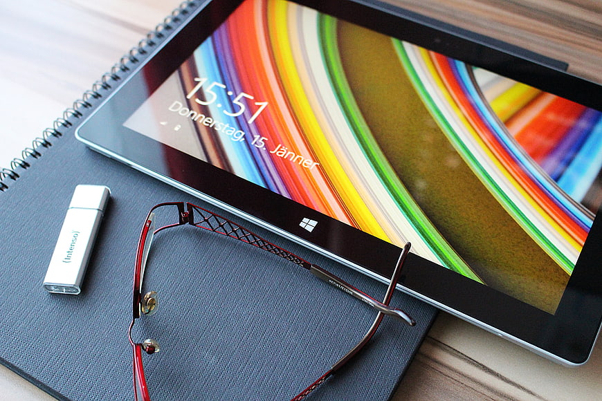Tablet with glasses and USB drive on notebook