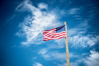 American flag waving against blue sky with clouds