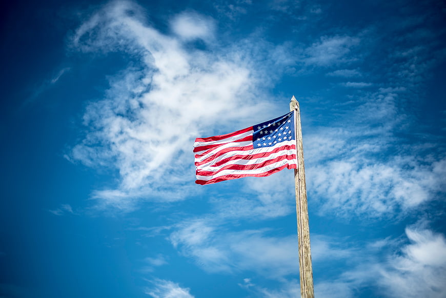 American flag waving against blue sky with clouds