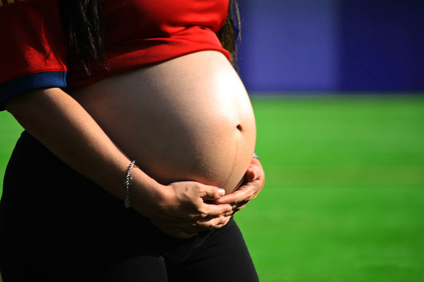Pregnant woman holding belly outdoors