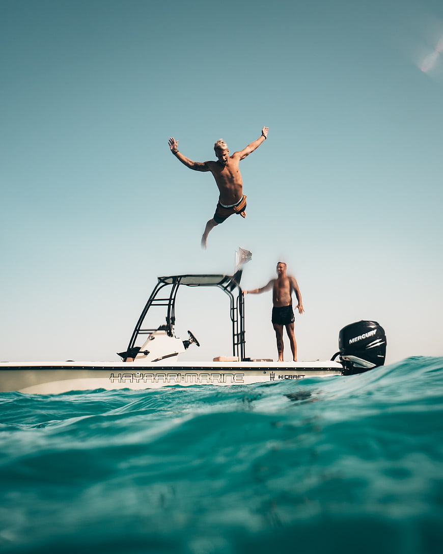 Man Jumping Off Boat Into Ocean Water