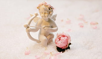 Cupid figurine with pink rose in snow