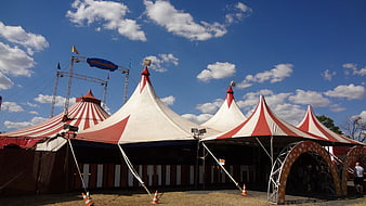 Red and white striped circus tents under a bright blue sky