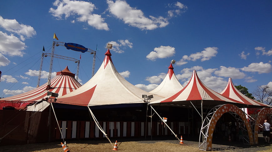 Red and white striped circus tents under a bright blue sky