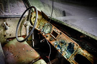 Rusty vintage car interior with deteriorated dashboard and steering wheel
