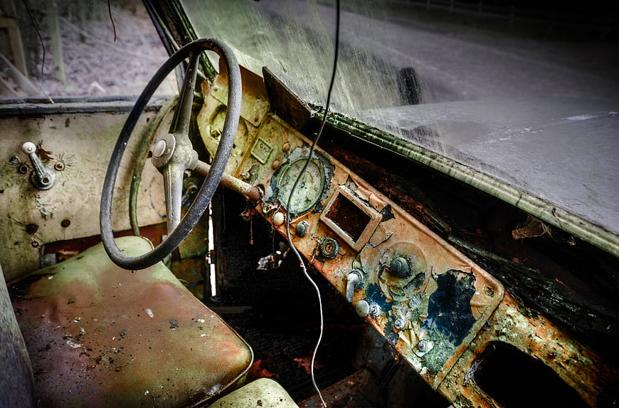 Rusty vintage car interior with deteriorated dashboard and steering wheel