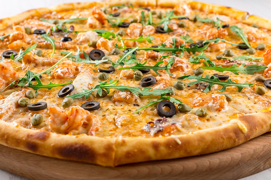Delicious Shrimp Pizza with Arugula and Olives on Wooden Board