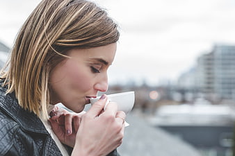 Woman Sipping Hot Coffee on Urban Balcony