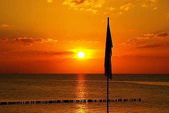 Silhouette of a beach flag at sea sunset