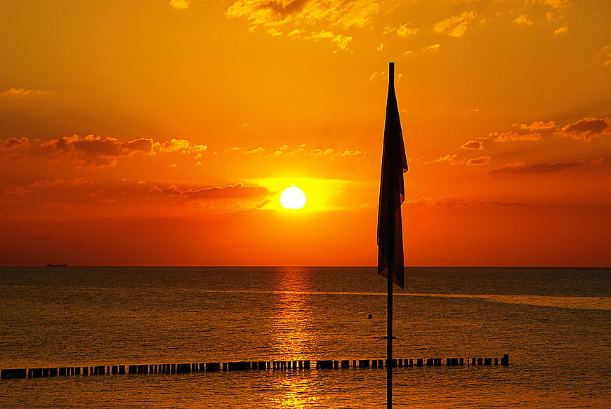 Silhouette of a beach flag at sea sunset
