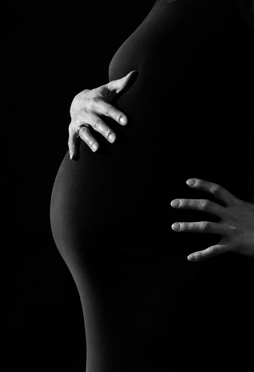Black and white pregnant woman holding belly