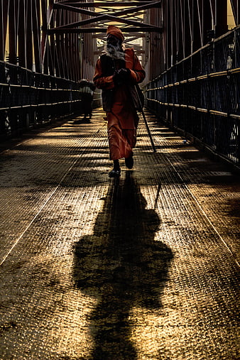 Sikh man walking on bridge with long shadow