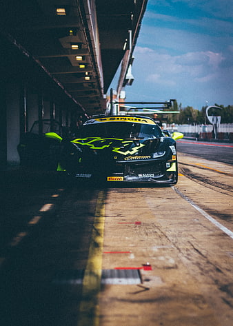 Black Ferrari race car in pit lane with neon green accents