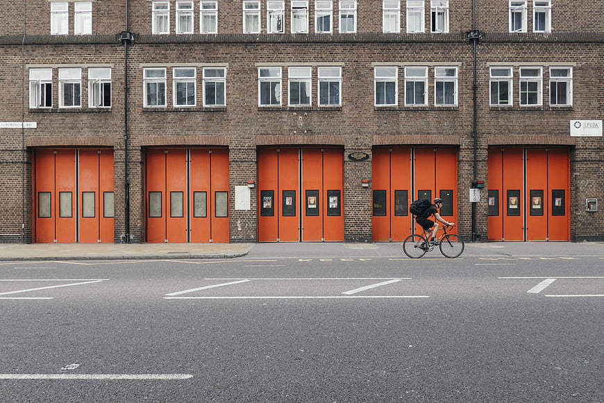 Cyclist riding past brick building with orange garage doors
