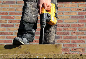 Carpenter Using Yellow Impact Drill On Wooden Board