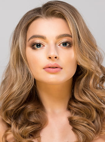 Studio Portrait Of Young Woman With Wavy Blonde Hair And Blue Eyes