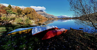 Colorful Kayaks on Lake Shore with Autumn Mountains