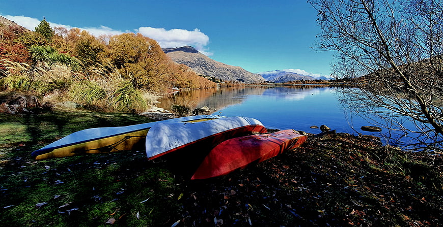 Colorful Kayaks on Lake Shore with Autumn Mountains