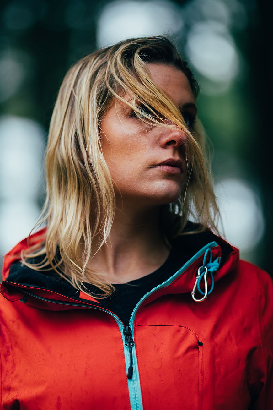 Blonde woman in red jacket with windblown hair outdoors