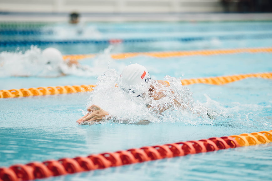 Swimmer performing butterfly stroke in pool lane
