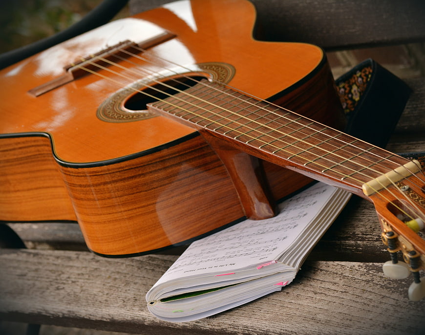 Acoustic Guitar and Songbook on Wooden Bench