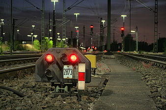 Red railway signal light on tracks at dusk
