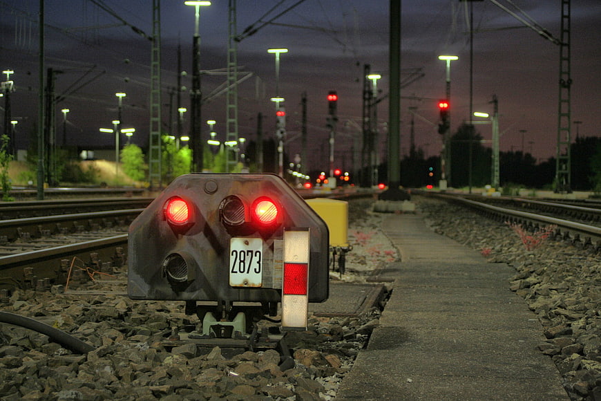 Red railway signal light on tracks at dusk