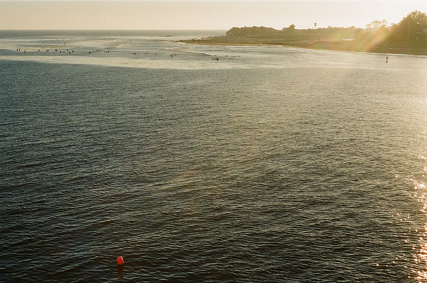 Surfers in Ocean at Golden Hour with Red Buoy