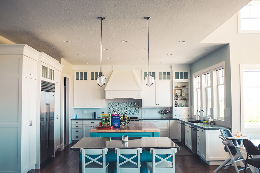Modern Kitchen Interior With White Cabinetry And Teal Island
