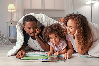Happy family reading book together under blanket indoors