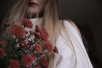 Woman with long blonde hair holding red chrysanthemums