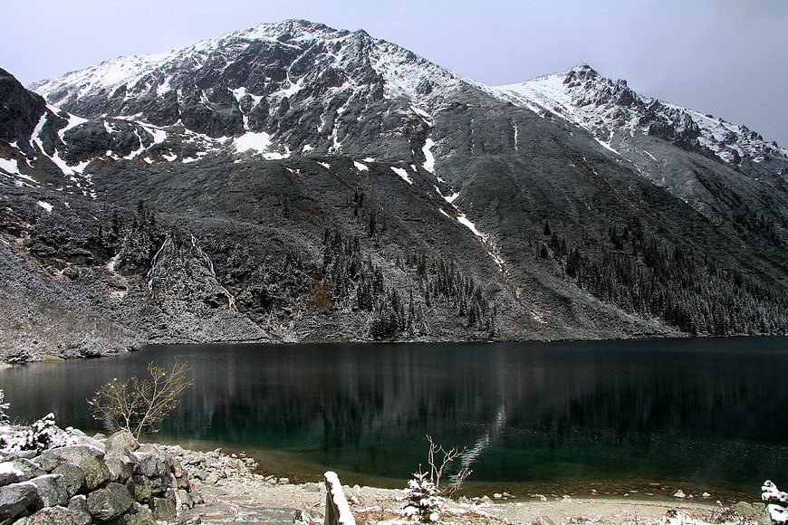 Snowy mountain peak reflected in calm alpine lake