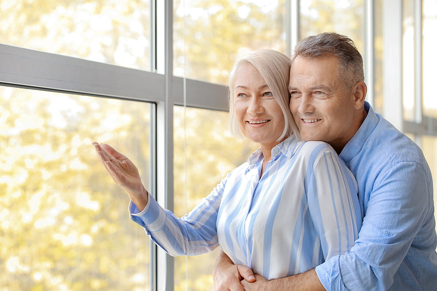 Happy Senior Couple Embracing by Window