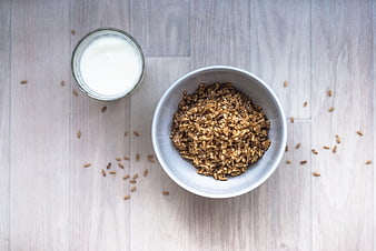 Bowl of Brown Rice and Glass of Milk on Light Wood Table